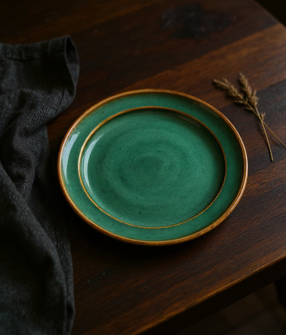 Remoxila Emerald Green glazed stoneware plate on a dark oak table with dramatic light